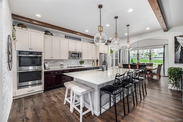 kitchen with tasteful backsplash, appliances with stainless steel finishes, dark wood-type flooring, a sink, and beamed ceiling