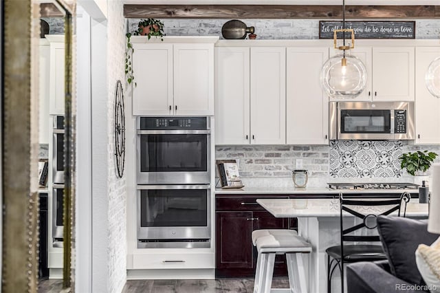 kitchen with white cabinetry, light countertops, appliances with stainless steel finishes, backsplash, and pendant lighting