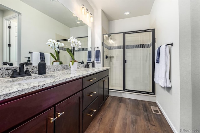 full bathroom with wood finished floors, a stall shower, a sink, and visible vents