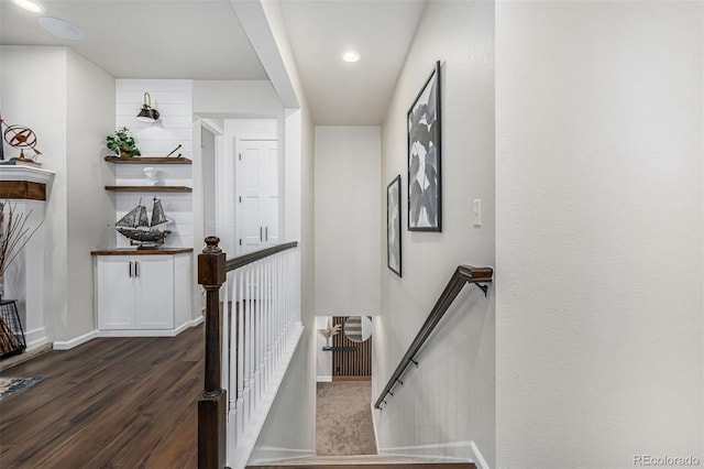 corridor with dark wood-style floors, baseboards, and an upstairs landing