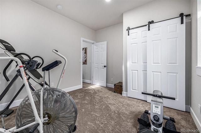 exercise area with a barn door, carpet, and baseboards