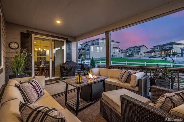 patio terrace at dusk featuring an outdoor living space with a fire pit and a residential view