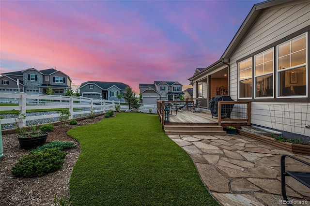 yard at dusk featuring a fenced backyard, a residential view, and a wooden deck