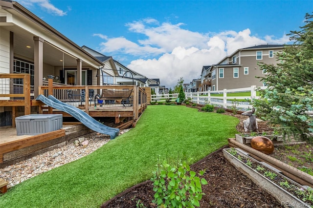 view of yard featuring a garden, a fenced backyard, a residential view, and a deck