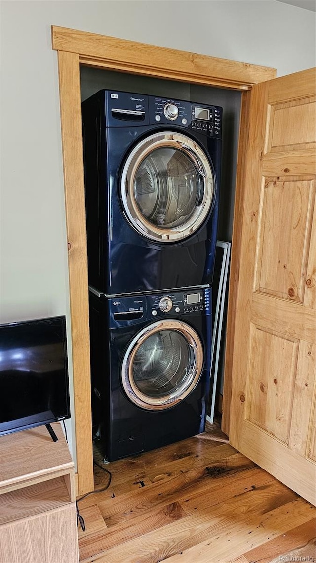 washroom with stacked washing maching and dryer and wood finished floors