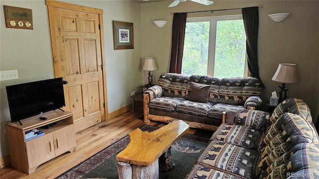 living area with light wood-style floors, baseboards, and a ceiling fan