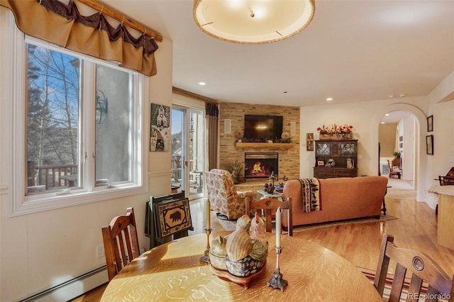 725 Sun Valley Dr, Woodland Park, CO 80863 - dining room with arched walkways, a baseboard radiator, a stone fireplace, light wood-style floors, and recessed lighting