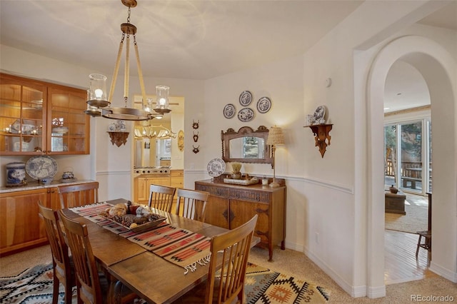 725 Sun Valley Dr, Woodland Park, CO 80863 - dining space featuring a chandelier, arched walkways, baseboards, and light carpet