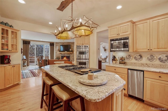 725 Sun Valley Dr, Woodland Park, CO 80863 - kitchen featuring light brown cabinetry, appliances with stainless steel finishes, light wood finished floors, a breakfast bar, and recessed lighting