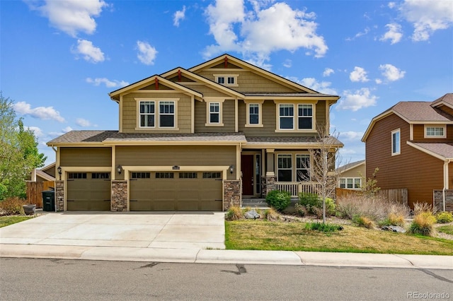 craftsman-style house with a garage, covered porch, concrete driveway, and stone siding
