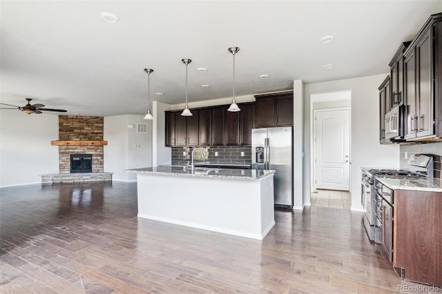 kitchen featuring backsplash, stainless steel appliances, a ceiling fan, and open floor plan