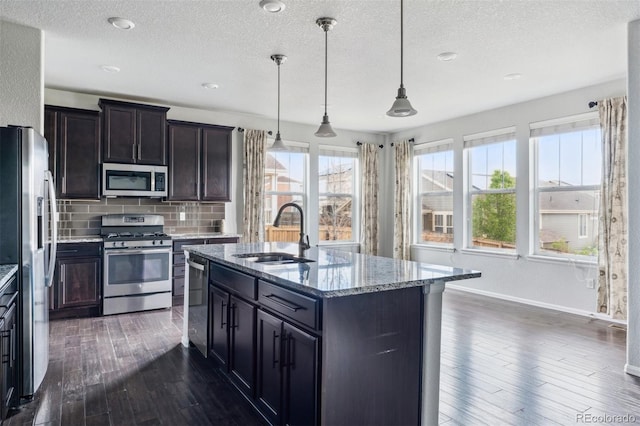 kitchen with a sink, a textured ceiling, appliances with stainless steel finishes, and dark wood-style floors