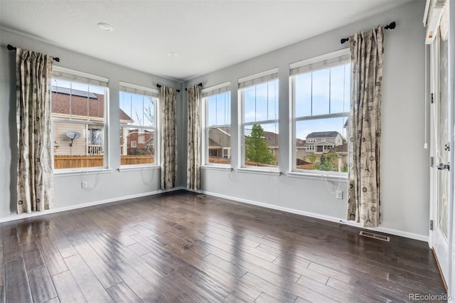 empty room featuring baseboards, visible vents, and wood finished floors