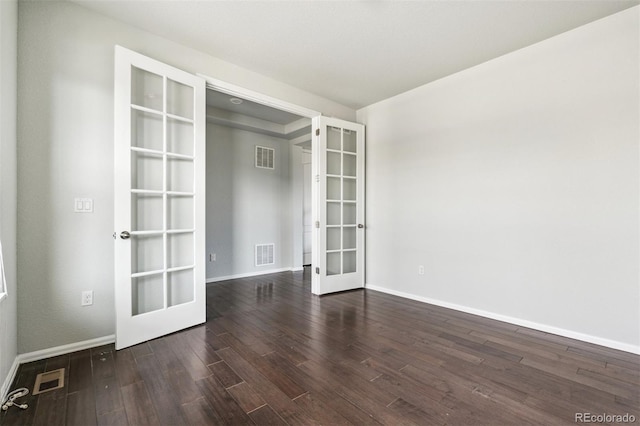 unfurnished room with dark wood-style flooring, baseboards, visible vents, and french doors