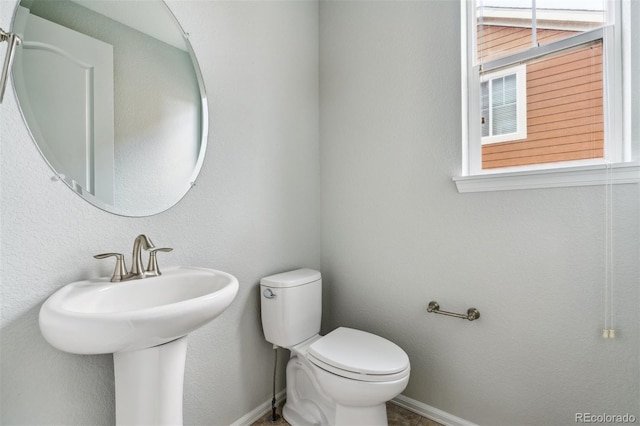 half bath featuring baseboards, a sink, and toilet