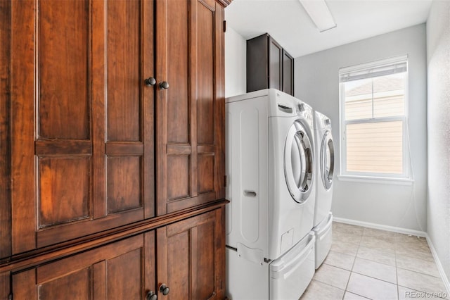 laundry room featuring baseboards, cabinet space, washing machine and dryer, and light tile patterned flooring
