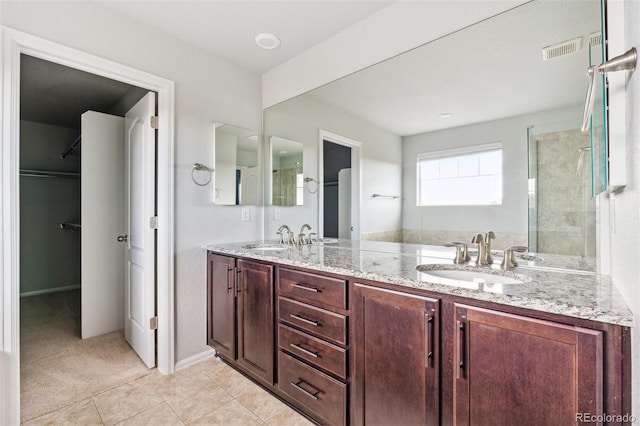 full bathroom featuring a sink, a walk in closet, double vanity, and visible vents