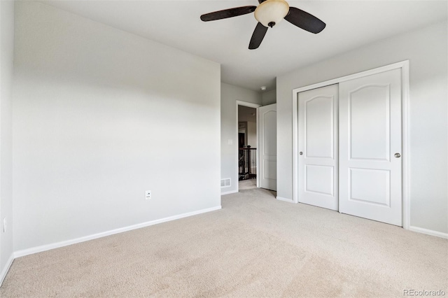 unfurnished bedroom featuring carpet floors, visible vents, a closet, baseboards, and a ceiling fan