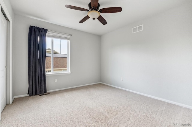 empty room with baseboards, a ceiling fan, light colored carpet, and visible vents