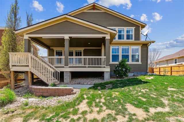back of property featuring a lawn, fence, and stairway