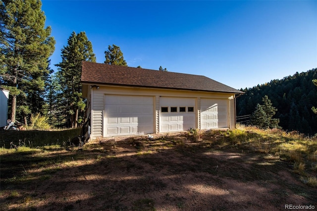 detached garage featuring a view of trees