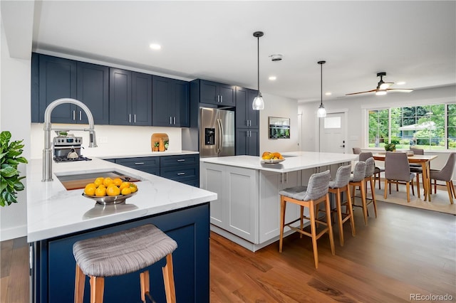 404 S Oneida Way, Denver, CO 80224 - kitchen with stainless steel refrigerator with ice dispenser, a breakfast bar, light wood finished floors, recessed lighting, and decorative light fixtures