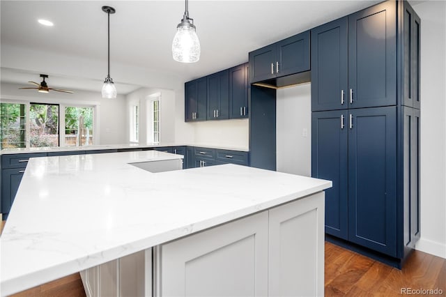 404 S Oneida Way, Denver, CO 80224 - kitchen with blue cabinets, light stone countertops, a ceiling fan, a peninsula, and wood finished floors