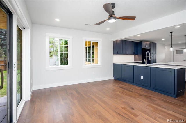 404 S Oneida Way, Denver, CO 80224 - kitchen with wood finished floors, light countertops, a peninsula, blue cabinets, and recessed lighting