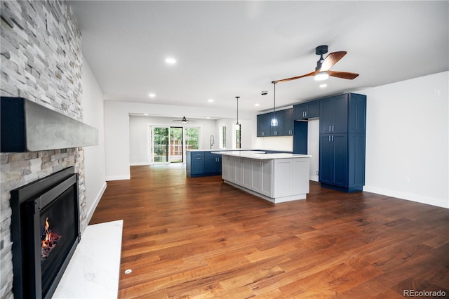 404 S Oneida Way, Denver, CO 80224 - kitchen with ceiling fan, blue cabinets, a kitchen island, light countertops, and a fireplace