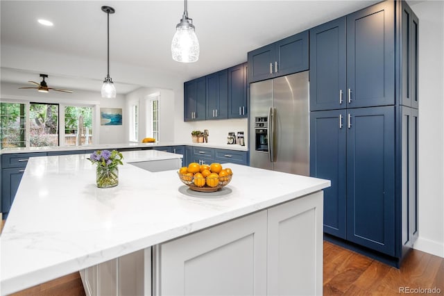 404 S Oneida Way, Denver, CO 80224 - kitchen with stainless steel fridge with ice dispenser, blue cabinets, a peninsula, and light stone countertops
