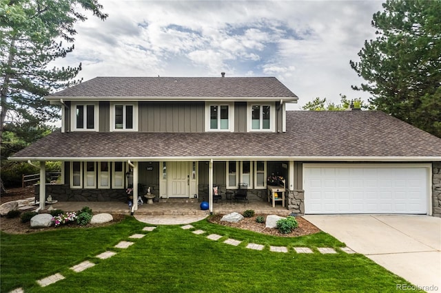 view of front of property with a garage, a front yard, and covered porch