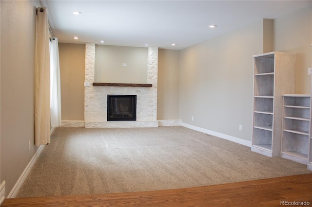 unfurnished living room with a stone fireplace and carpet flooring