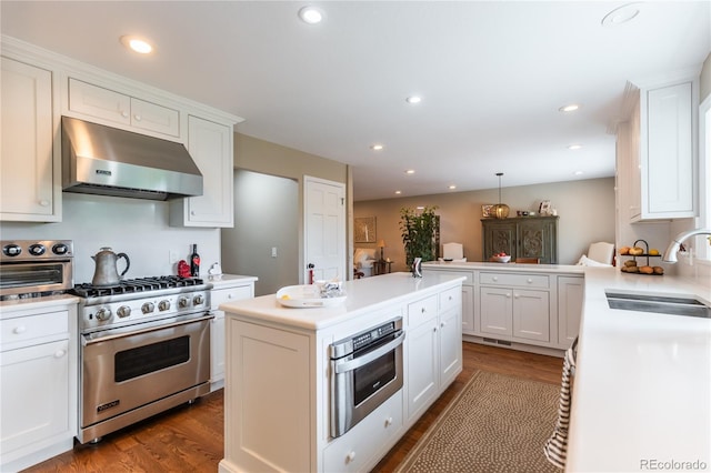 kitchen with sink, appliances with stainless steel finishes, kitchen peninsula, pendant lighting, and range hood