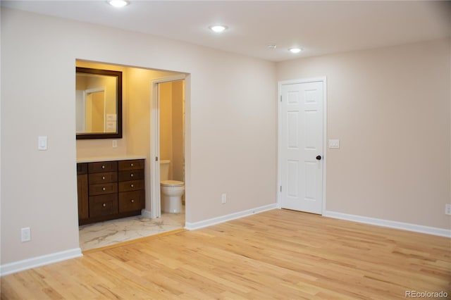 unfurnished bedroom featuring light wood-type flooring and ensuite bath