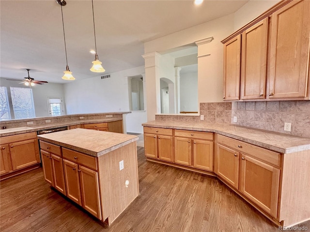 kitchen featuring light countertops, wood finished floors, a kitchen island, and tasteful backsplash