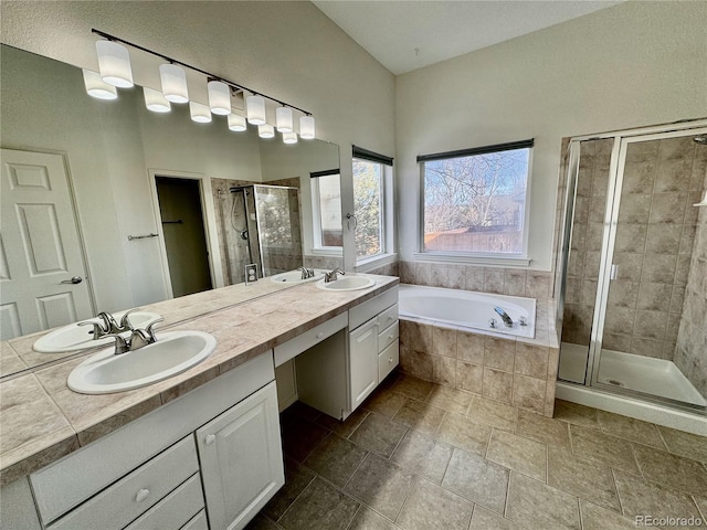 bathroom featuring a bath, a shower stall, double vanity, and a sink