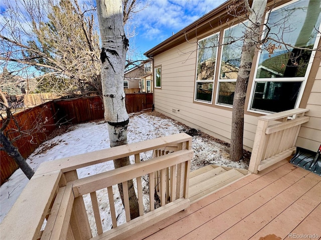 snow covered deck with a fenced backyard