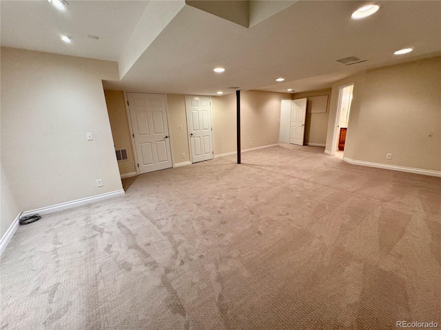 finished basement with light carpet, visible vents, baseboards, and recessed lighting