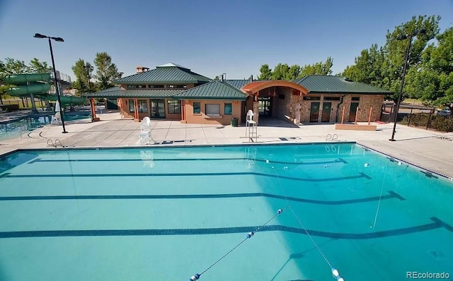 community pool featuring a patio and a water slide