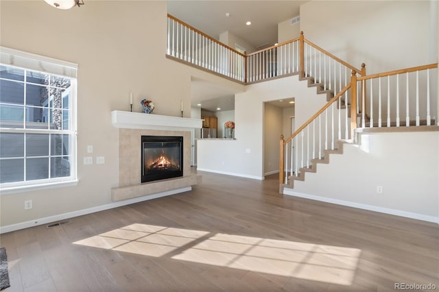 unfurnished living room featuring a fireplace, a high ceiling, and hardwood / wood-style flooring