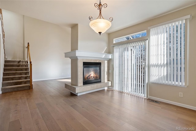 unfurnished living room featuring hardwood / wood-style flooring and a tiled fireplace