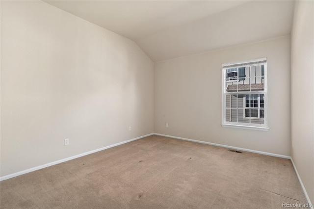 empty room with light colored carpet and vaulted ceiling