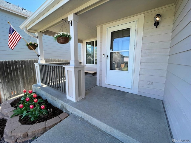 view of exterior entry with a porch and fence