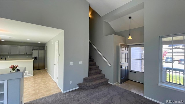 entrance foyer with visible vents, vaulted ceiling, baseboards, stairs, and light tile patterned flooring