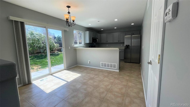 kitchen with visible vents, an inviting chandelier, a peninsula, light countertops, and stainless steel appliances