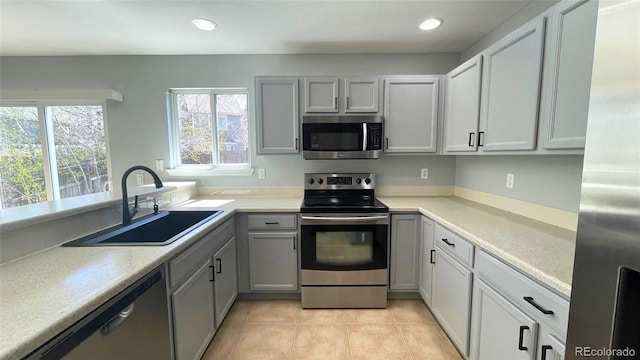 kitchen featuring appliances with stainless steel finishes, a sink, light tile patterned floors, light countertops, and recessed lighting