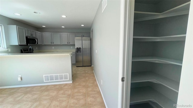 kitchen featuring visible vents, light countertops, gray cabinets, and stainless steel appliances