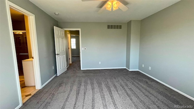unfurnished bedroom featuring ensuite bath, carpet floors, a ceiling fan, baseboards, and visible vents