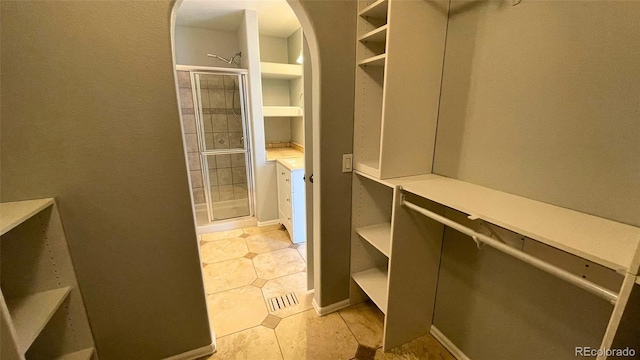 walk in closet featuring light tile patterned floors and arched walkways
