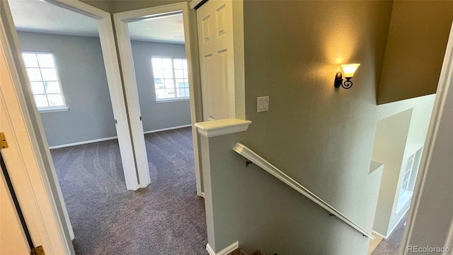 interior space with baseboards, an upstairs landing, and dark carpet